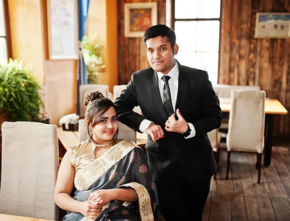 elegant-fashionable-indian-friends-couple-woman-saree-man-suit-posed-indoor-cafe_627829-1974